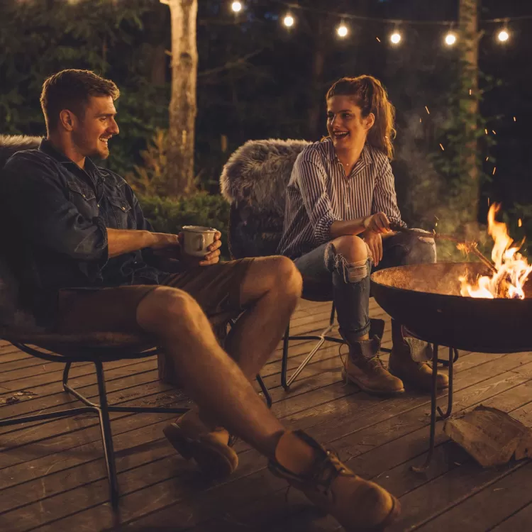 Couple enjoying a fire pit outside a glamping lodge